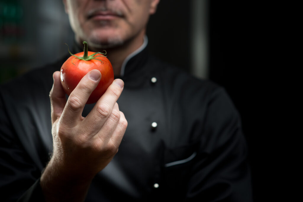 chef sostiene un tomate con su mano