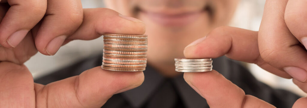 mano sostiene una pila de monedas y la otra mano una pila de monedas mas pequeña